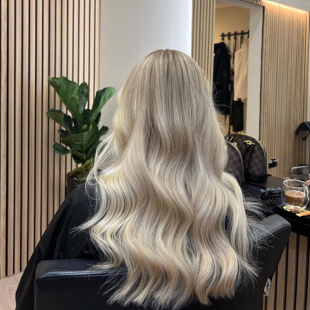 Kund med långt, vågigt blont hår efter lyckad frisörbehandling på LOOKS sthlm