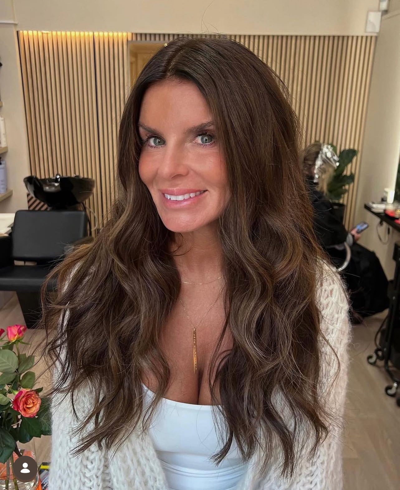 Kvinna med långt, vågigt hår efter frisörbesök hos LOOKS sthlm