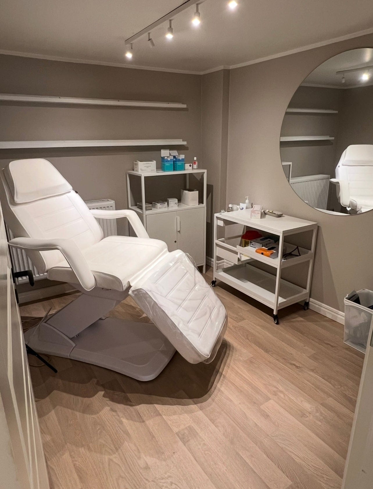 Modern skönhetssalong i Stockholm hos LOOKS sthlm med vit behandlingsstol och produkt­hyllor