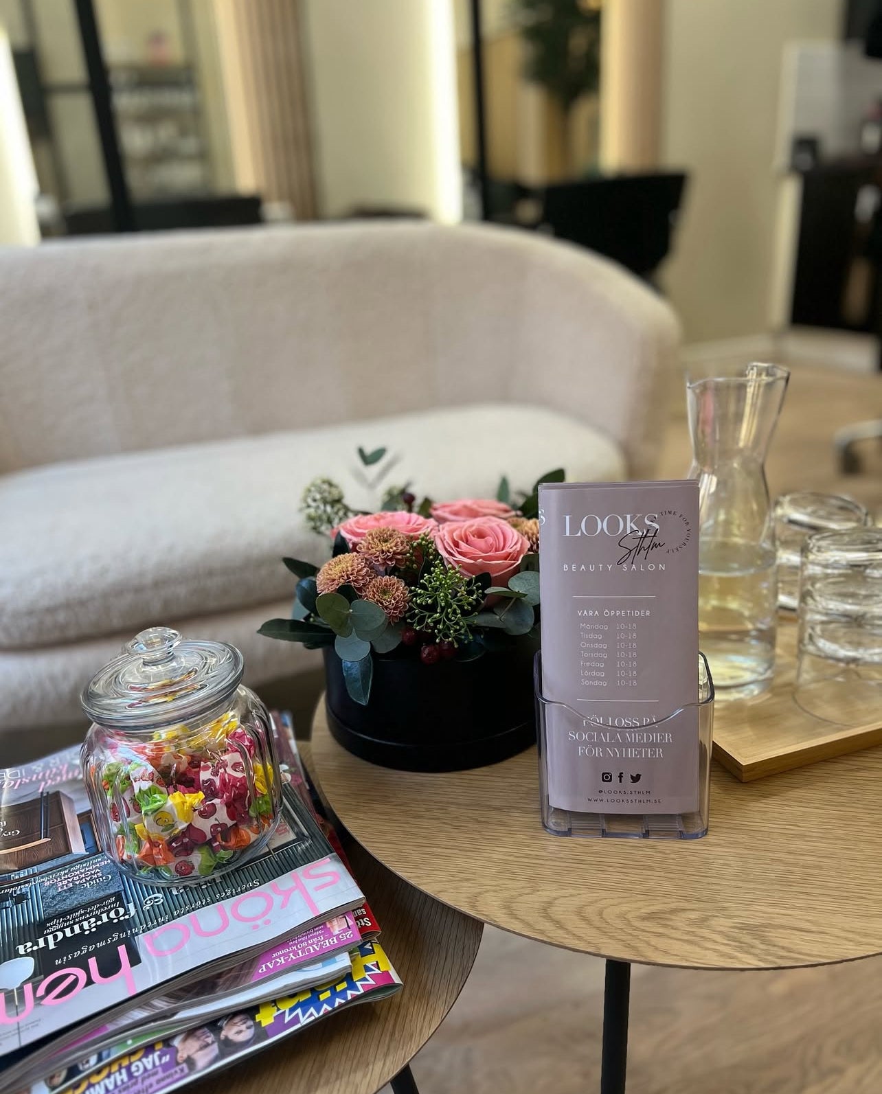 LOOKS sthlm lounge med blommor, vatten och salongens visitkort på bordet