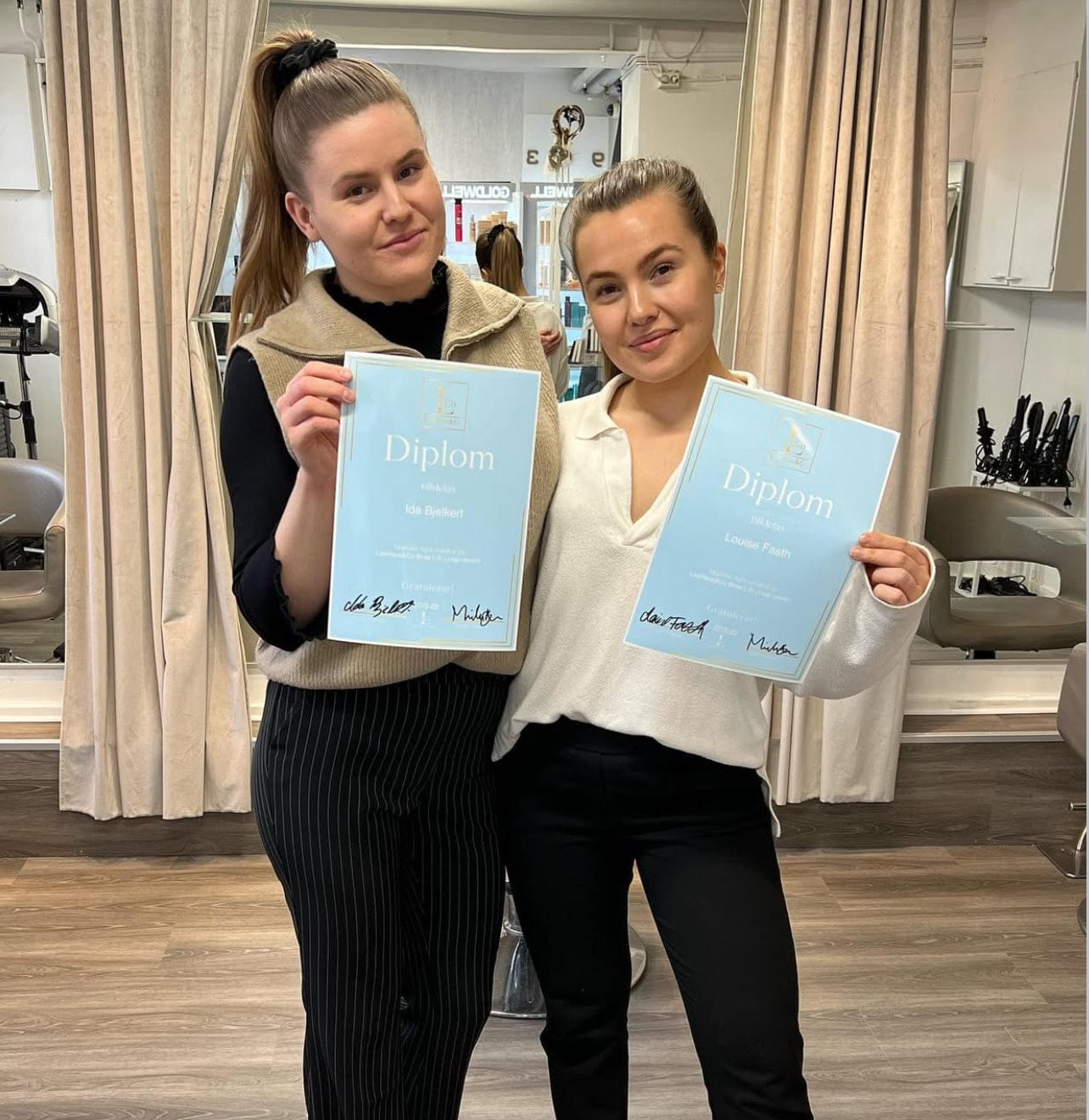Två personer firar med diplom efter utbildning hos LOOKS sthlm